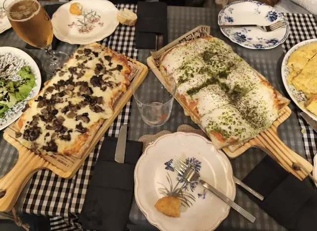 Dos pizzas en tabla sobre mesa de cuadros